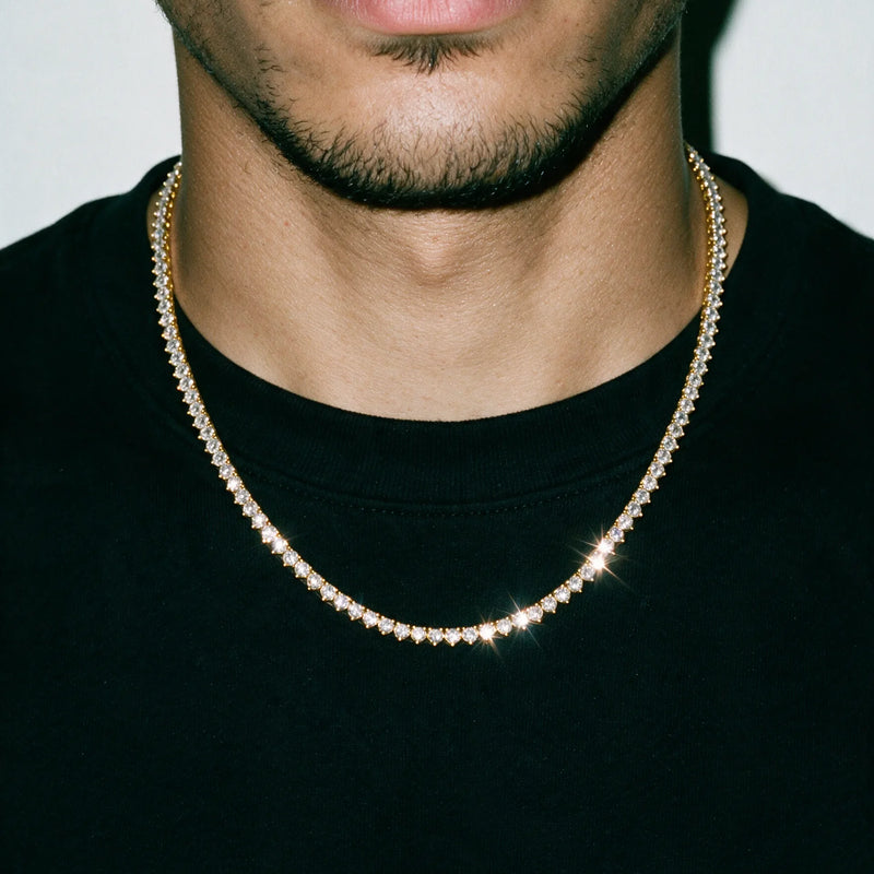 Gold 3MM tennis chain worn over a black tee, chest and chin in frame